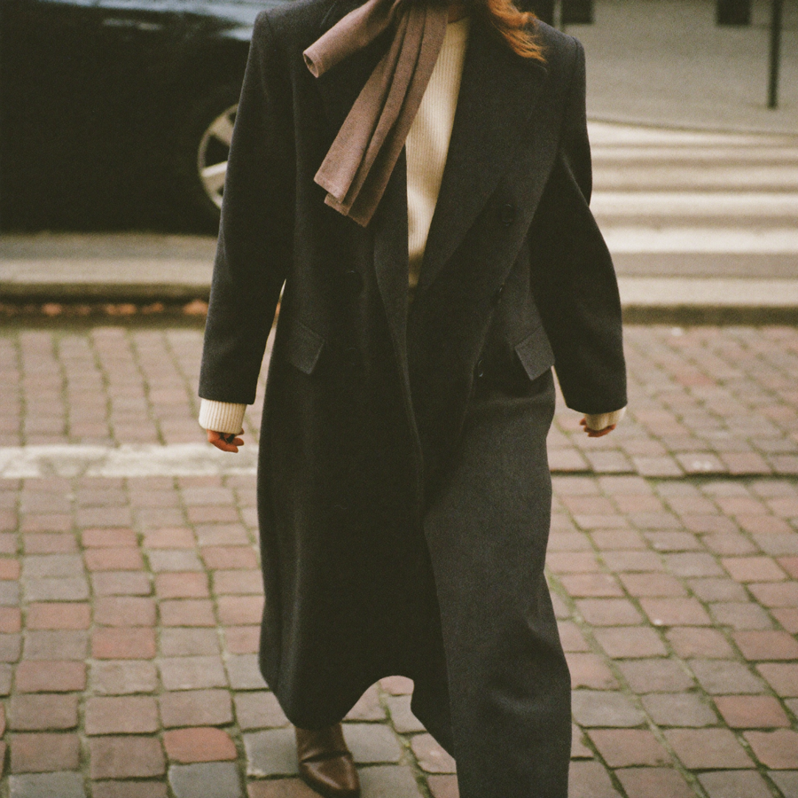 Customer in a charcoal double-breasted wool coat on a cobbled street