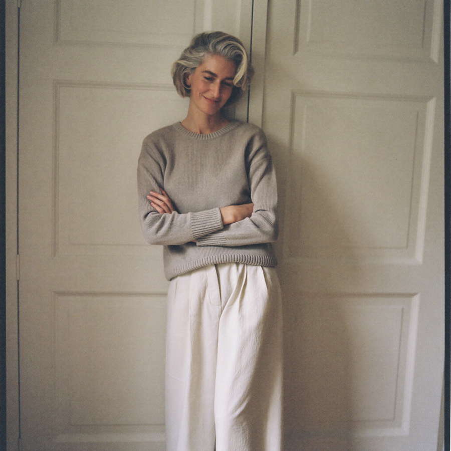 Customer in an oatmeal ribbed knit jumper and cream wide-leg trousers