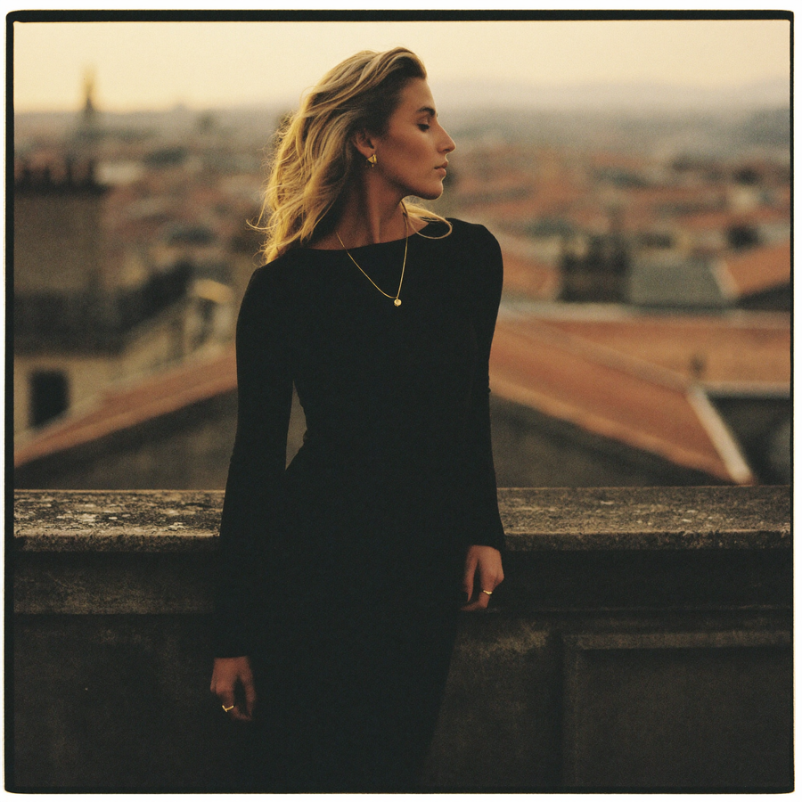 Customer in a black midi dress on a balcony at golden hour