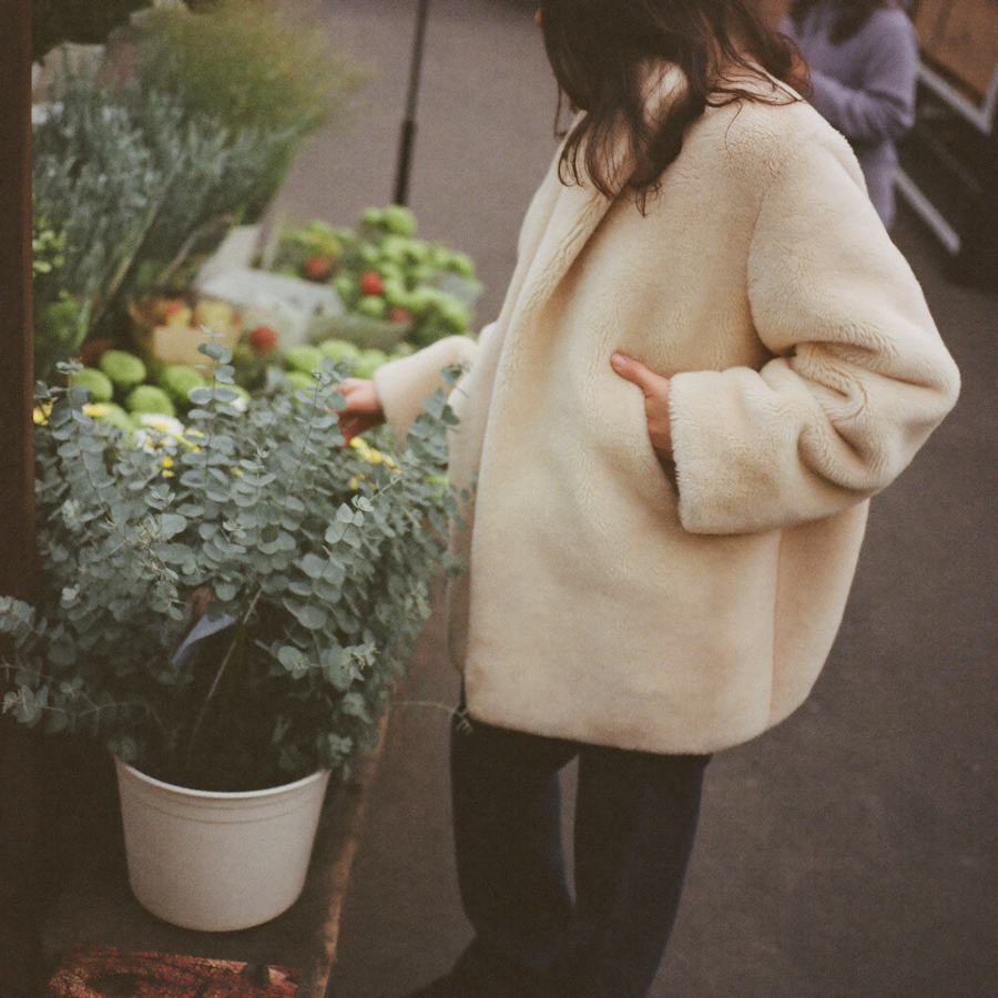 Customer in a cream faux fur coat at a flower market